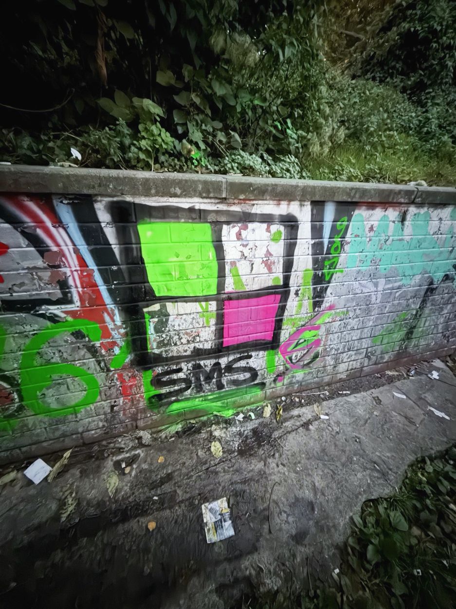 Sage's green and pink window tag with SMS painted on a brick wall in Berlin